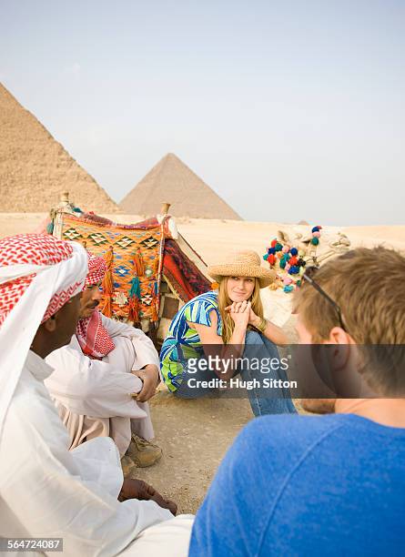 tourists talking with egyptians in front of pyramids - hugh sitton fotografías e imágenes de stock