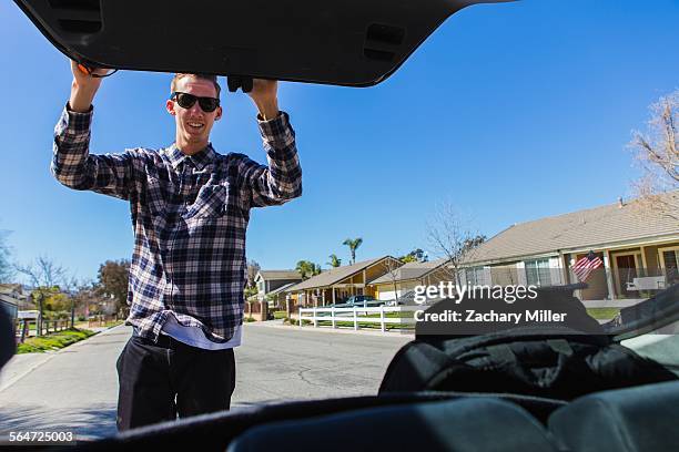 young man closing car boot, upland, california, usa - closing car boot fotografías e imágenes de stock