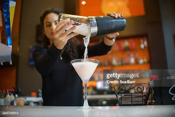 young female bartender pouring cocktail from shaker in cocktail bar - barman fotografías e imágenes de stock