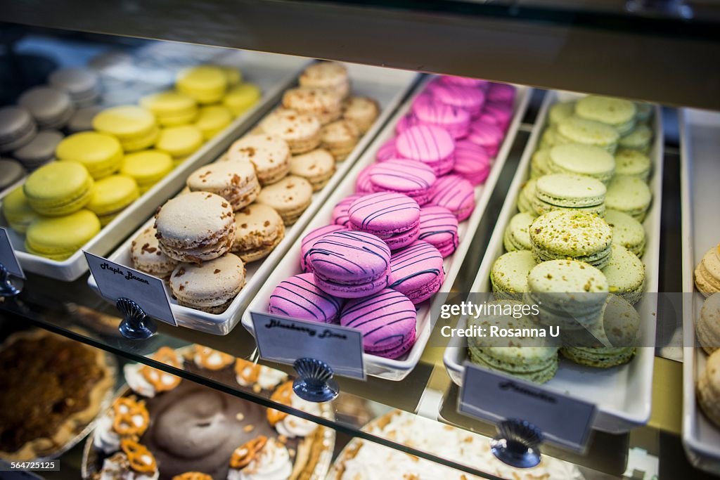 Macarons in trays in display cabinet, close-up