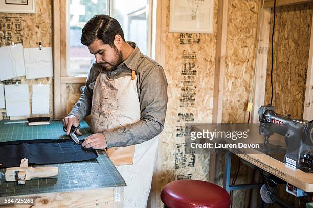 tailor cutting textile fabric on workshop bench - lauren taylor stock pictures, royalty-free photos & images