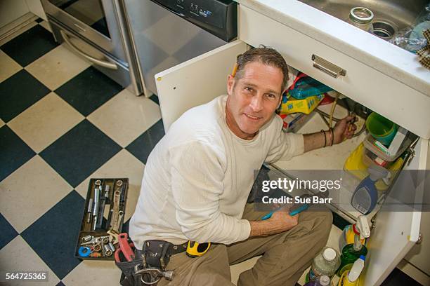 handyman fixing kitchen sink pipe - handyman smiling stock pictures, royalty-free photos & images