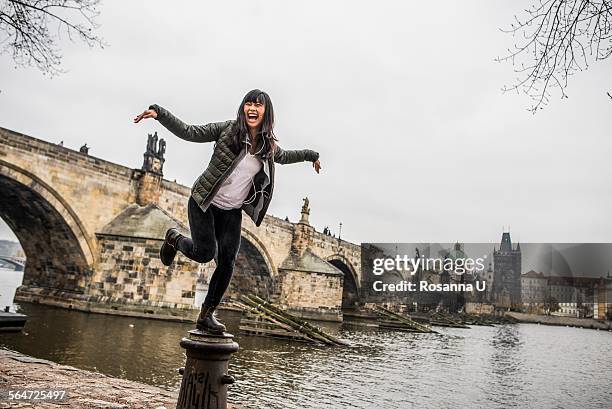 woman balancing on bollard in front of charles bridge, prague - prague people stock pictures, royalty-free photos & images