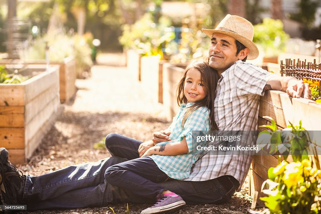 Portrait of girl in community garden sitting on fathers knee