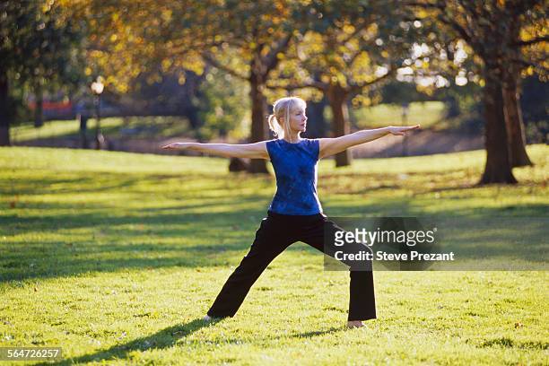 woman performing tai chi in park - woman and tai chi stock pictures, royalty-free photos & images