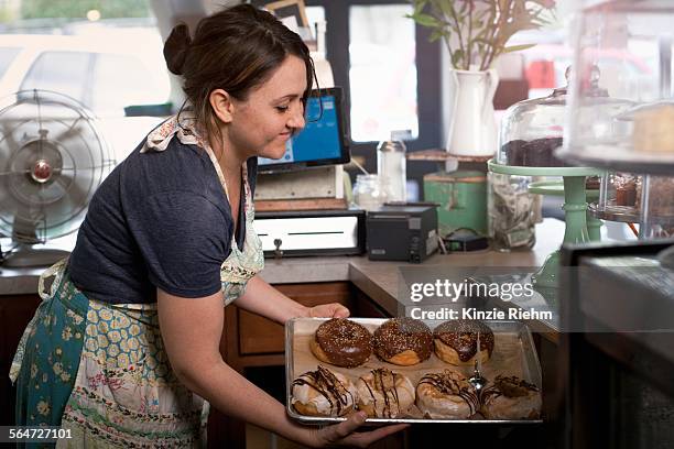 bakery owner placing tray of doughnuts into display case - sugar canister stock pictures, royalty-free photos & images