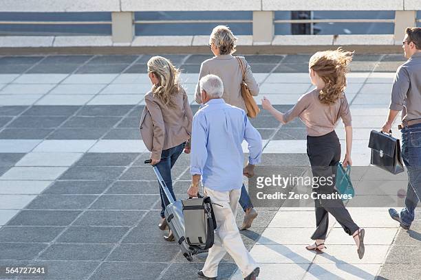 five adults walking across paving slabs - striding stock pictures, royalty-free photos & images