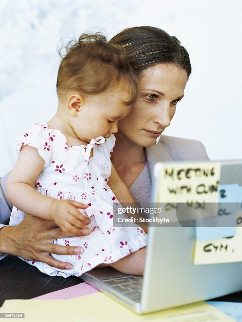 Businesswoman and her daughter using a laptop