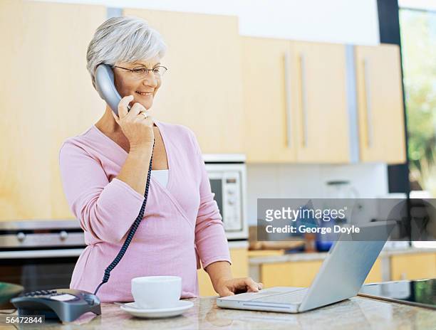 mature woman talking on a landline phone - landline telephone stock pictures, royalty-free photos & images