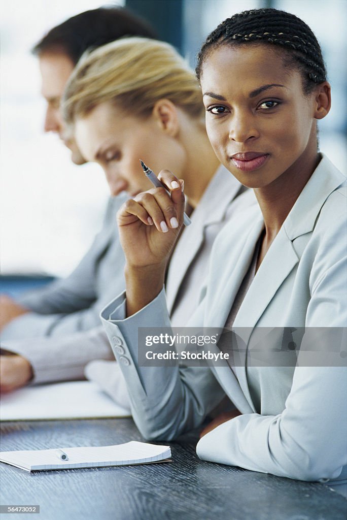 Two businesswomen and a businessman sitting next to each other in an office