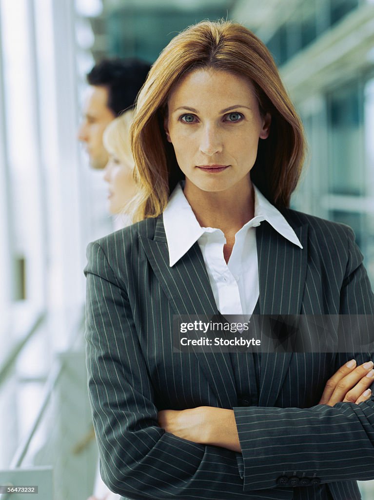 Portrait of a businesswoman standing with two business executives standing behind her