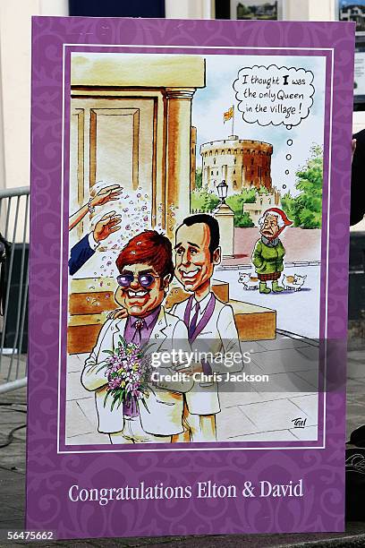 Cartoon on a banner depicting celebrity couple Sir Elton John and David Furnish stands on the street during their civil partnership ceremony at the...