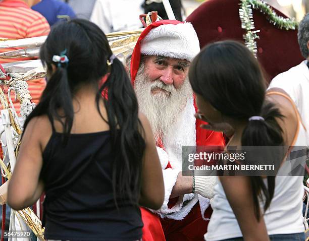 En chile los ninos pobres piden algo mas que un juguete al "Viejo Pascuero". Un anciano disfrazado de Papa Noel habla con dos ninas antes de tomarse...