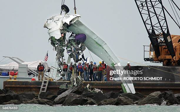 Investigators look at a portion of a wing and wheel well from a Grumman G-73T Turbine Mallard, a twin-engine amphibious aircraft as it is lifted from...
