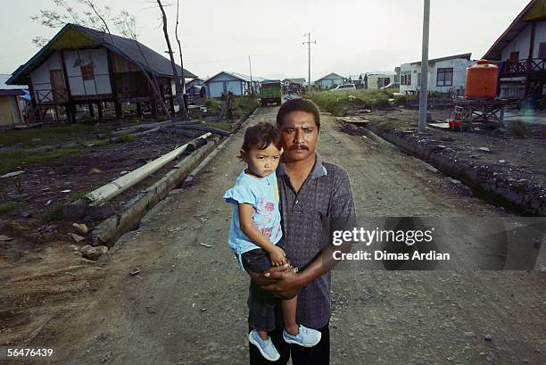 Tsunami survivor, widower Mustakaria and his three-year-old daughter Jihan Paradila stand on Tengku Muda Street in Kampung Jawa where they got...
