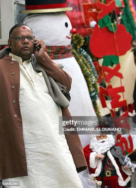 An Indian man talks on his mobile phone next to a giant styrofoam snowman and a Santa Claus doll at a market in New Delhi, 22 December 2005. Delhi...