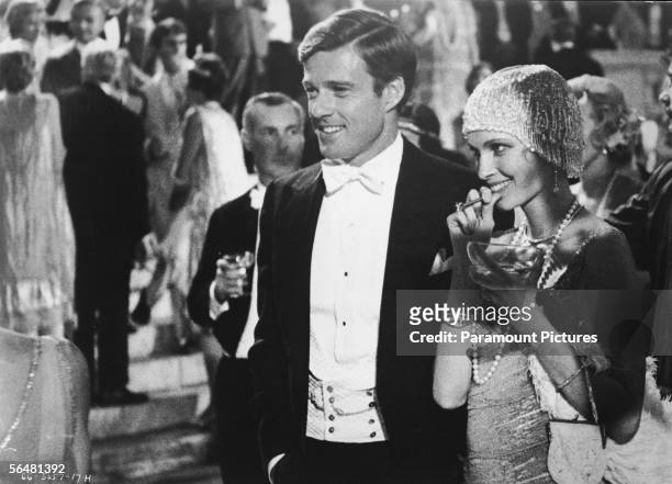 American actors Robert Redford, as Jay Gatsby, and Mia Farrow, as Daisy Buchanan, smile at a well-to-do party in a scene from 'The Great Gatsby,'...