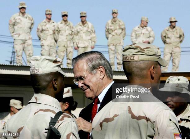 Secretary of Defense Donald Rumsfeld presents a medal of valor to U.S. Army Sgt. Kenneth Stover as soldiers watch from a rooftop during a medal...