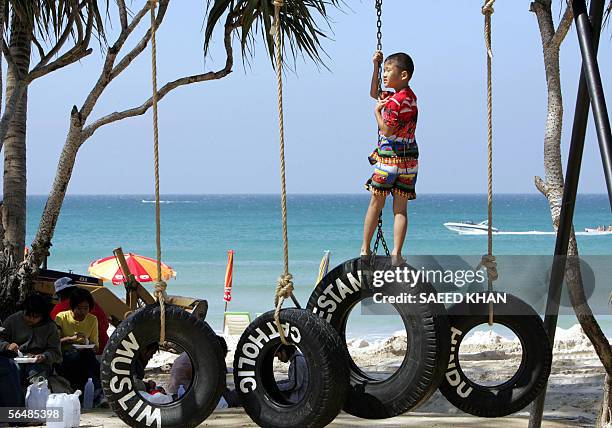 Boy balances himself on an art piece by Italian artist Paolo Canevari at the "Art For Andaman" exhibition on Patong beach in Thailand's southern...