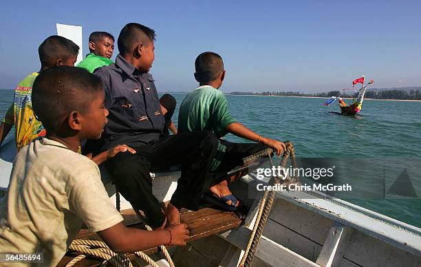 Children watch on as a memorial boat is set afloat during a Mokken Sea Gypsy memorial service held on Khuk Khok beach, December 24, 2005 in Khao Lak,...