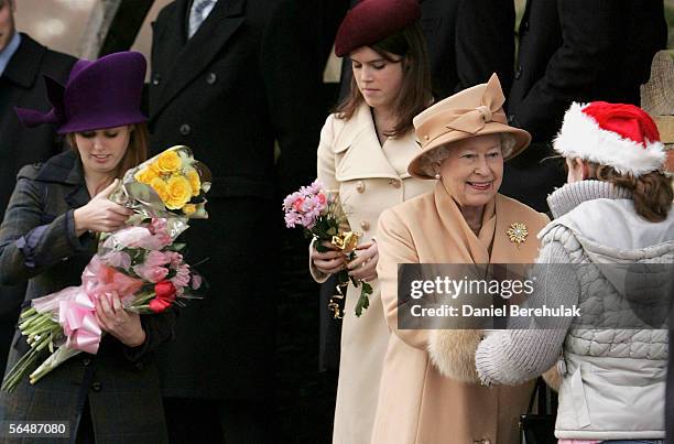 Britain's Queen Elizabeth II accepts bunches of flowers from well wishers and receives help from Britain's Princesses Beatrice and Eugene as she...