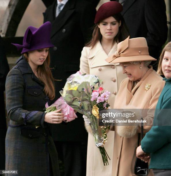 Queen Elizabeth II accepts bunches of flowers from well wishers and receives help from Britain's Princesses Beatrice and Eugenie as she leaves...