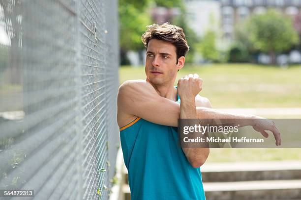 man stretching in park before exercise - adult male vest exercise stock pictures, royalty-free photos & images