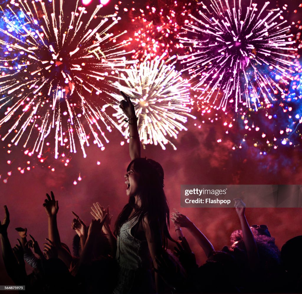 Woman amongst crowd enjoying firework display