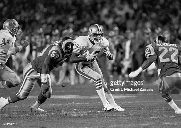 Wide receiver John Taylor of the San Francisco 49ers evades linebacker Fred Strickland and safety Vince Newsome of the Los Angeles Rams during the...