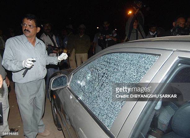 An Indian security inspects a car damaged after a gunman opened fire on the campus of the Indian Institute of Science campus in Bangalore, 28...