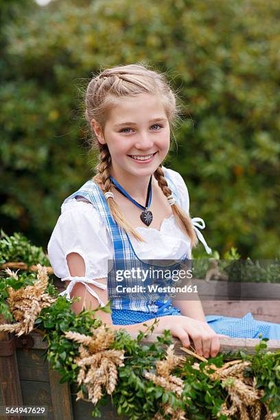 germany, luneburger heide, portrait of smiling blond girl wearing dirndl sitting on harvest wagon - harvest festival 個照片及圖片檔