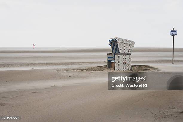 germany, schleswig-holstein, st peter-ording, hooded beach chair in stormy weather - mar de wadden fotografías e imágenes de stock