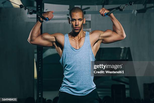 young man training at cable crossover in gym - rope handle stock pictures, royalty-free photos & images
