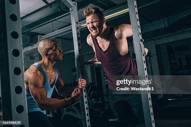 two friends exercising dips at power rack in gym - sports pain stock-fotos und bilder