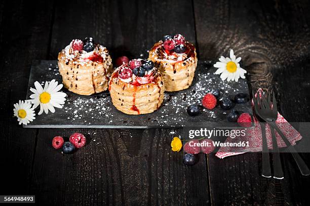 filo pastry tartlets filled with vanilla ice cream and whipped cream garnished with blueberries and raspberries - brick photos et images de collection