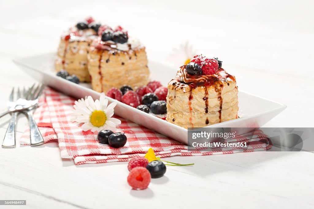Filo pastry tartlets filled with vanilla ice cream and whipped cream garnished with blueberries and raspberries