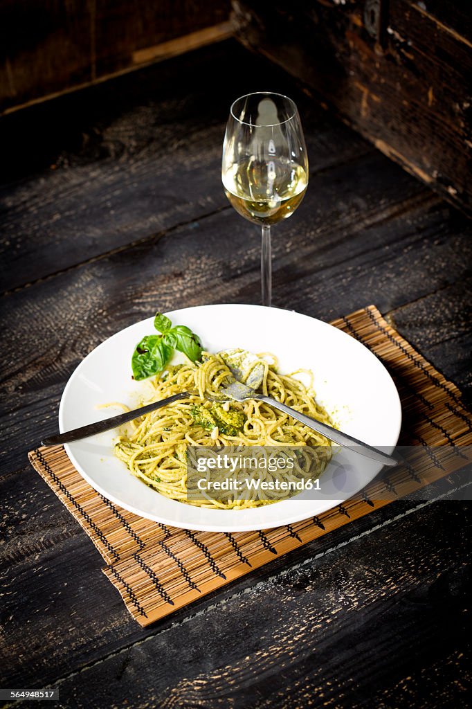 Plate of spaghetti with pesto Genovese and glass of white wine