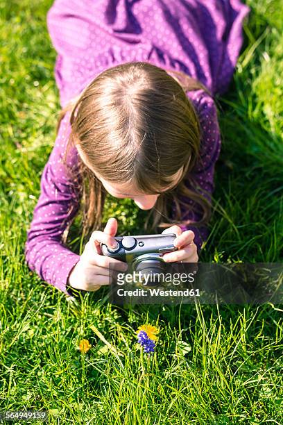 little girl lying on meadow photographing a flower - kind camera bloemen stockfoto's en -beelden