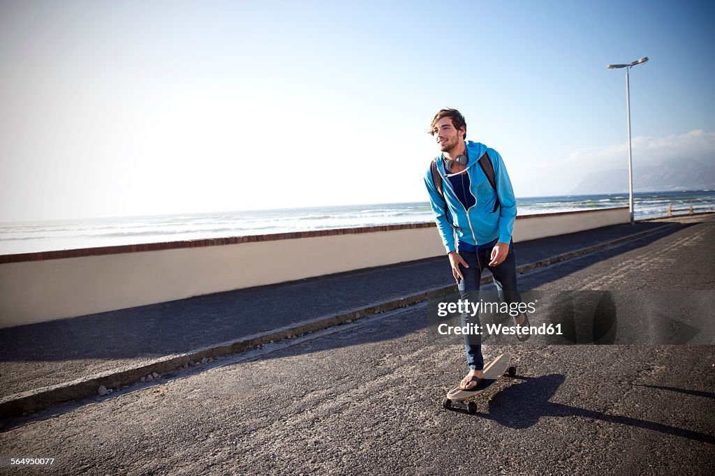 Young man with longboard on coastal road