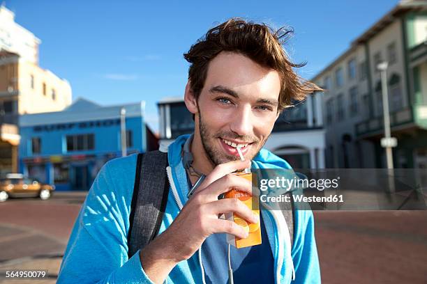 portrait of smiling young man drinking from juice box - carton stock pictures, royalty-free photos & images