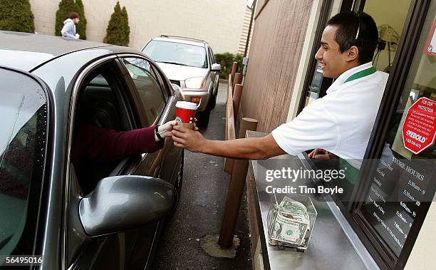 Starbucks worker Freddie Arteaga assists a customer with her drink order at a Starbucks drive-thru December 28, 2005 in Wheeling, Illinois. Starbucks...