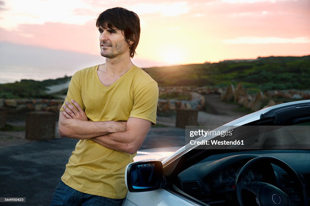 South Africa, smiling man at parked car at sunrise