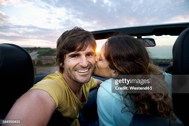 south africa, happy couple in convertible at the coast at sunrise - auto küssen stock-fotos und bilder