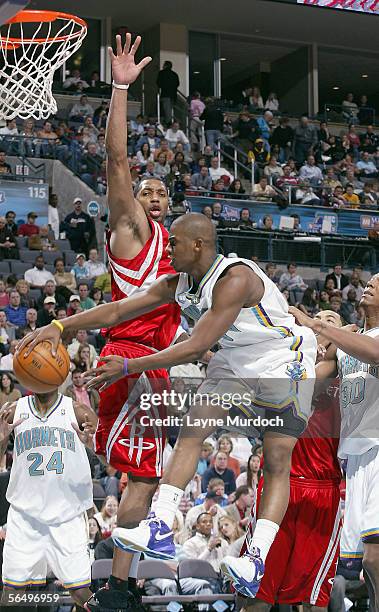 Chris Paul of the New Orleans/Oklahoma City Hornets passes the ball around Tracy McGrady of the Houston Rockets at the Ford Center in Oklahoma City,...