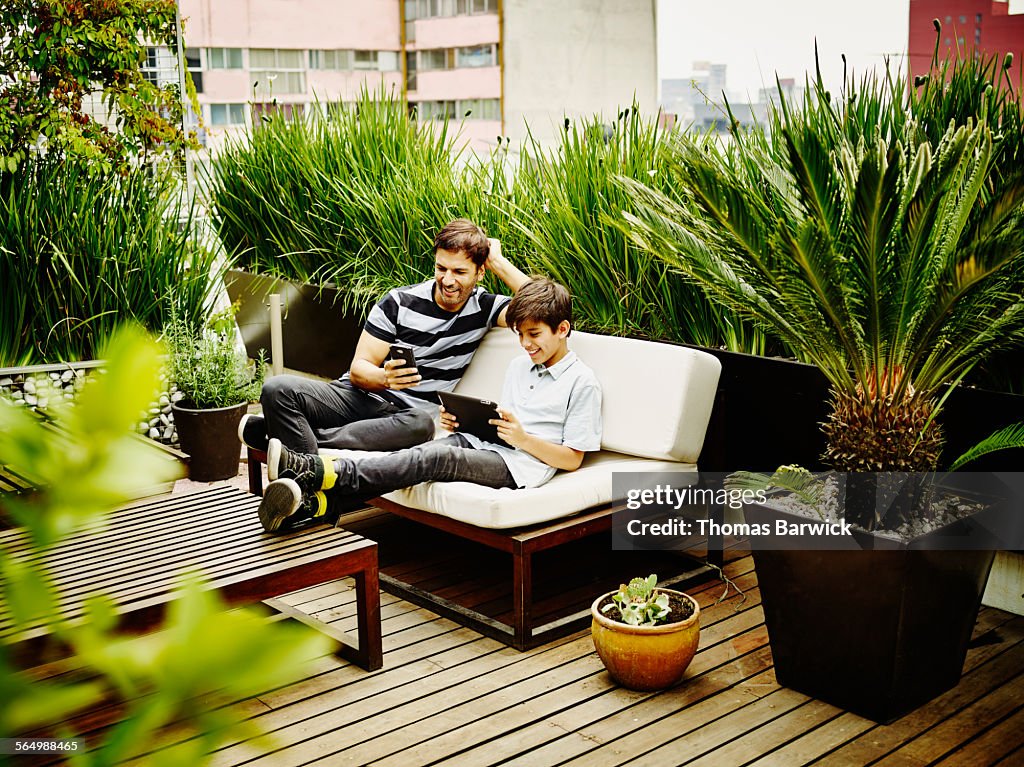 Smiling father and son sitting together on terrace