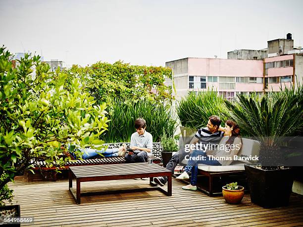 smiling family sitting together on rooftop terrace - family greenery bildbanksfoton och bilder