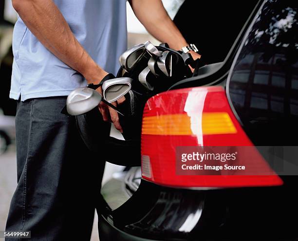 man putting golf clubs in car boot - golf clubs stock pictures, royalty-free photos & images