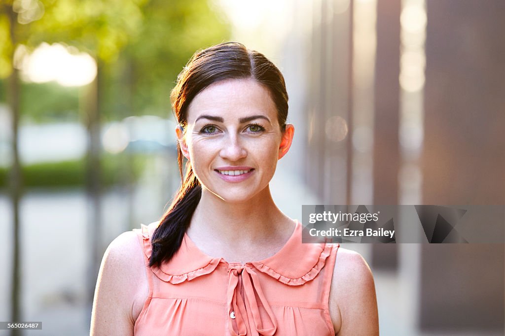 Confident smiling woman on tree-lined sidewalk