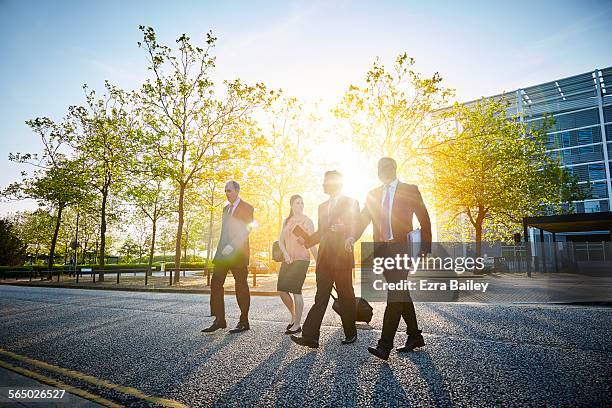 colleagues walk and talk in the city sun - business man woman walking stock pictures, royalty-free photos & images