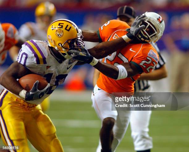 Joseph Addai of the LSU Tigers stiff-arms Kelly Jennings of the Miami Hurricanes in the Chick-Fil-A Peach Bowl on December 30, 2005 at the Georgia...